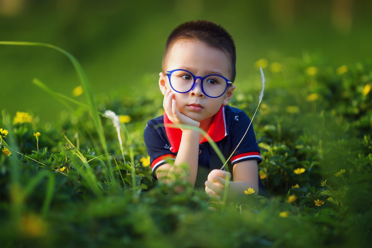 little boy with glasses looks deep in thought