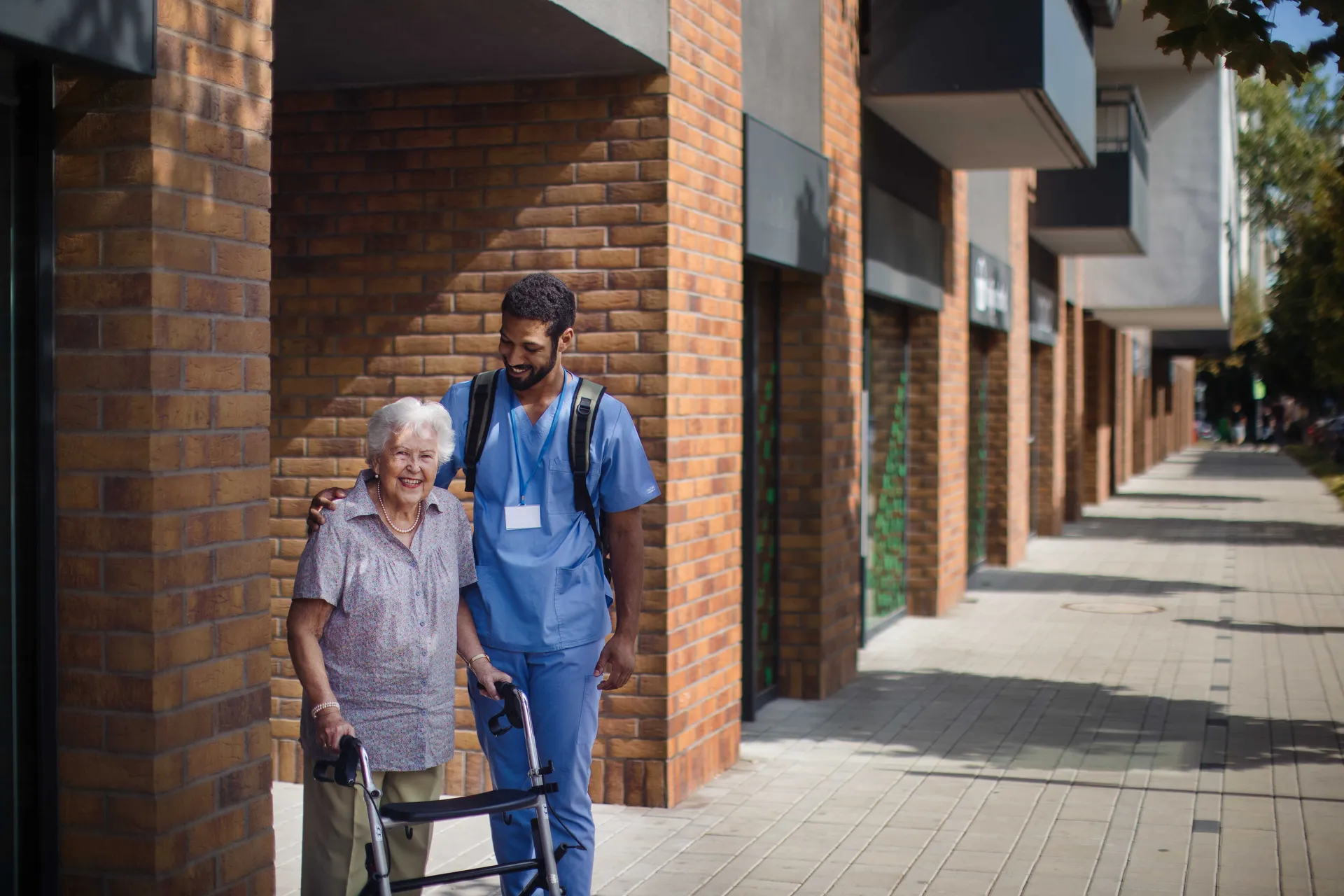 Caregiver walking with senior woman client in front of a nurishing home.
