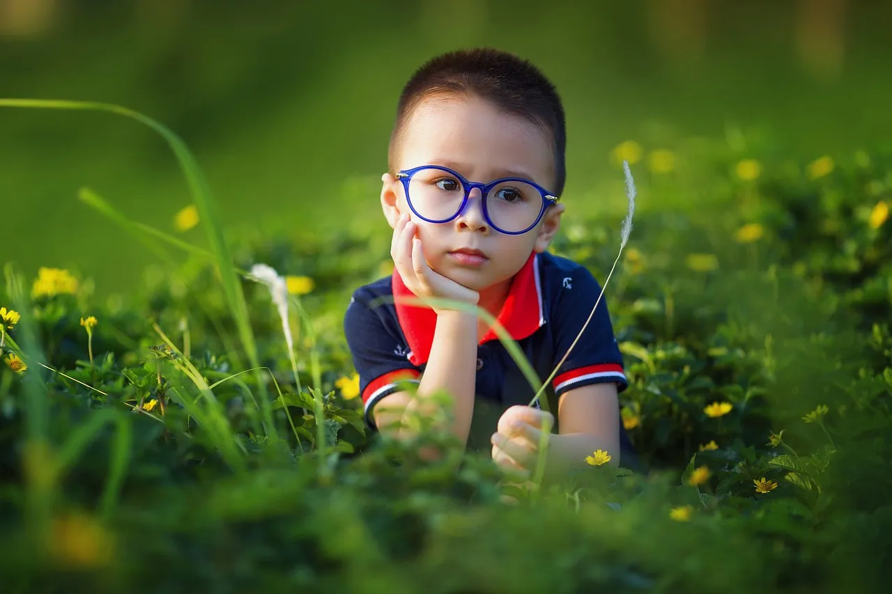 little boy with glasses looks deep in thought